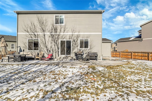 snow covered back of property featuring a patio