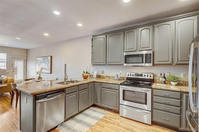 kitchen featuring stainless steel appliances, gray cabinets, and a sink