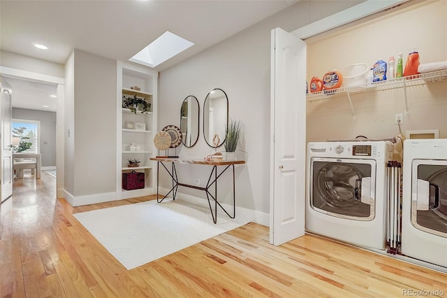 laundry area featuring built in shelves, washer and clothes dryer, wood finished floors, laundry area, and baseboards