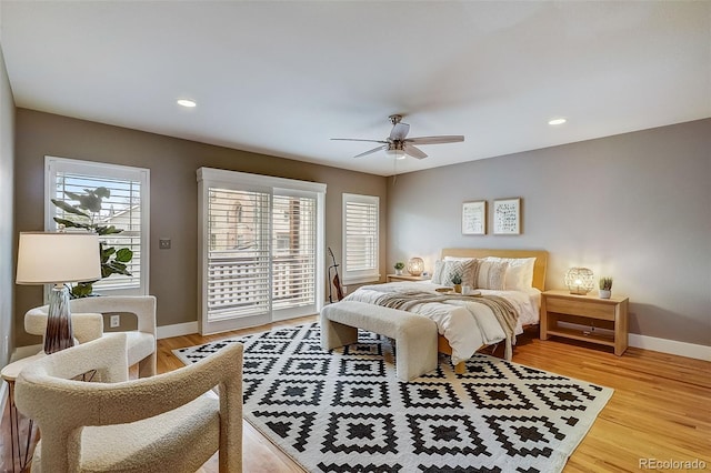 bedroom featuring light wood-type flooring, access to outside, multiple windows, and baseboards