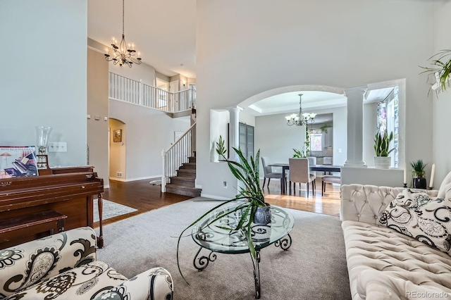 14096 Roaring Fork Cir, Broomfield, CO 80023 - living room featuring a high ceiling, arched walkways, a chandelier, decorative columns, and wood finished floors