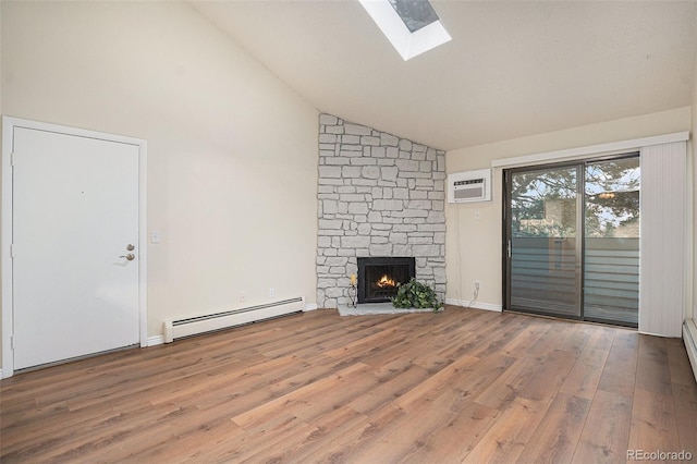 unfurnished living room featuring a baseboard heating unit, a skylight, wood finished floors, an AC wall unit, and a stone fireplace