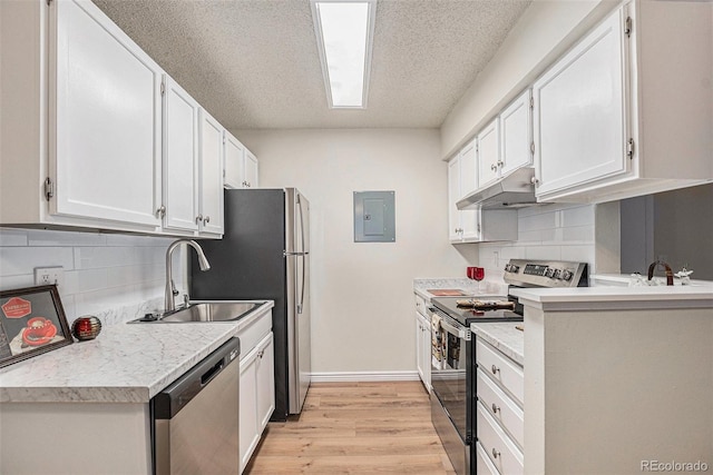 kitchen featuring stainless steel appliances, a sink, under cabinet range hood, white cabinetry, and light countertops