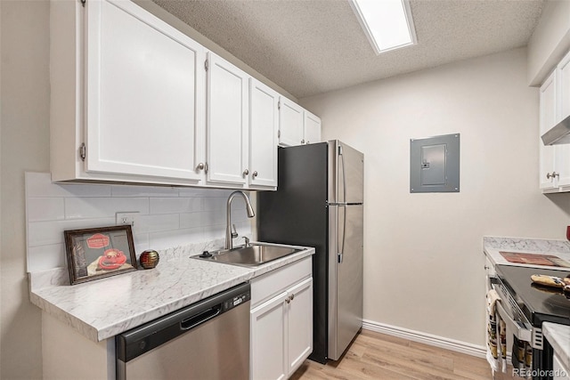 kitchen featuring appliances with stainless steel finishes, electric panel, a sink, light wood-type flooring, and white cabinets