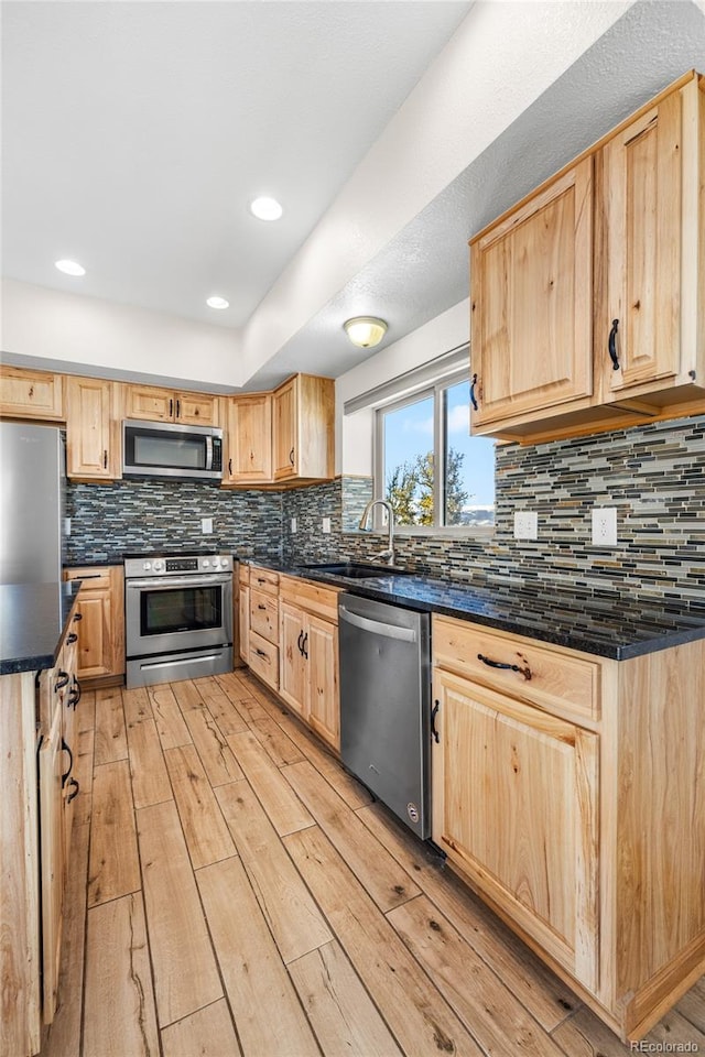 5844 Middle Fork Vis, Fairplay, CO 80440 - kitchen with appliances with stainless steel finishes, light brown cabinets, dark countertops, light wood finished floors, and tasteful backsplash