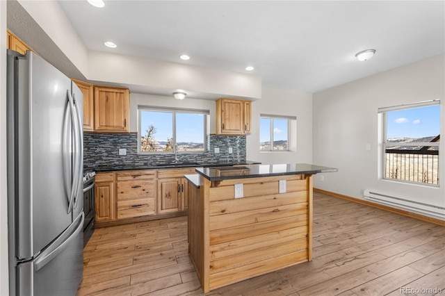 5844 Middle Fork Vis, Fairplay, CO 80440 - kitchen with stainless steel appliances, baseboard heating, light wood-style floors, dark countertops, and backsplash