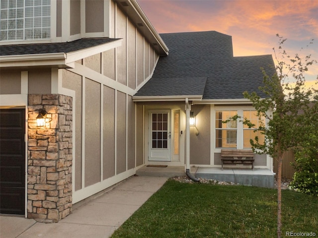 doorway to property with board and batten siding, a shingled roof, and stone siding