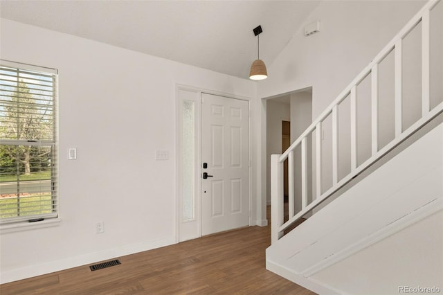 entryway featuring healthy amount of natural light, wood finished floors, stairs, lofted ceiling, and baseboards