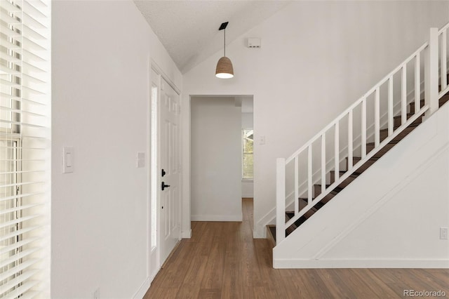 entryway featuring lofted ceiling, wood finished floors, and baseboards