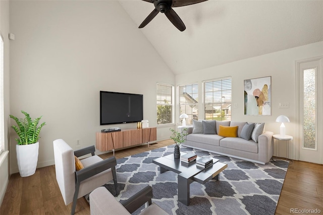 living area with high vaulted ceiling, ceiling fan, wood finished floors, and baseboards