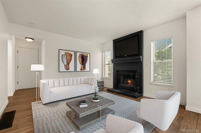 living area with wood finished floors, baseboards, and a brick fireplace