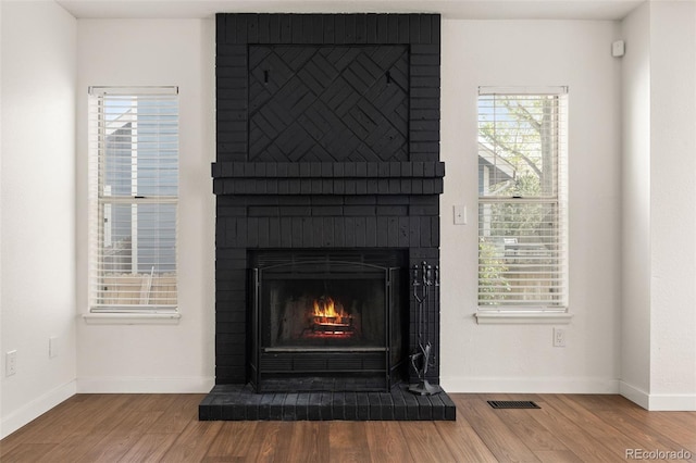 detailed view of wood finished floors, baseboards, and a fireplace