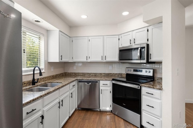 kitchen with appliances with stainless steel finishes, a sink, white cabinetry, dark wood-style floors, and recessed lighting