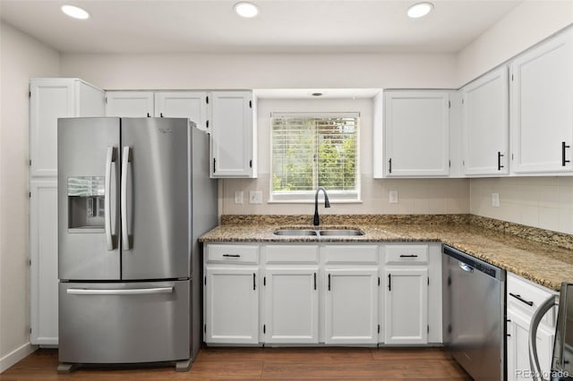 kitchen with appliances with stainless steel finishes, a sink, white cabinetry, recessed lighting, and light stone countertops