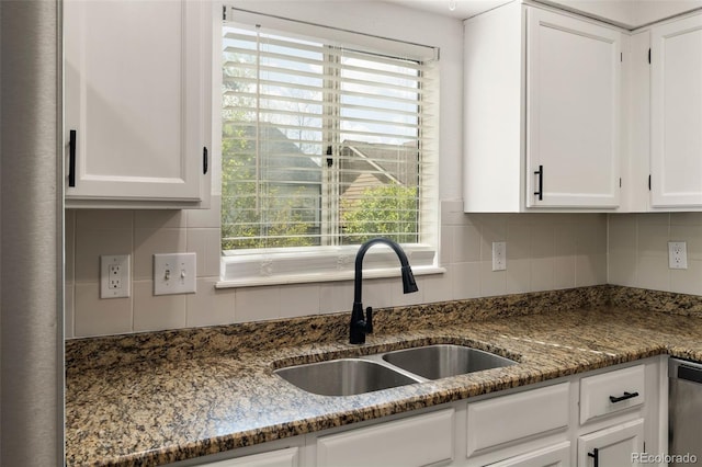 kitchen with a sink, white cabinetry, healthy amount of natural light, and dark stone countertops
