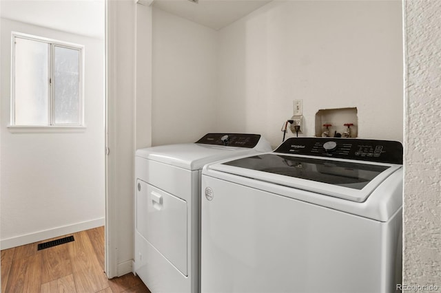 laundry area with washing machine and dryer, light wood finished floors, and baseboards