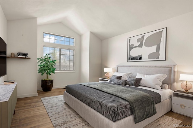 bedroom with lofted ceiling, wood finished floors, and baseboards