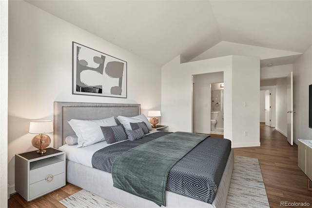 bedroom featuring lofted ceiling, wood finished floors, baseboards, and ensuite bath