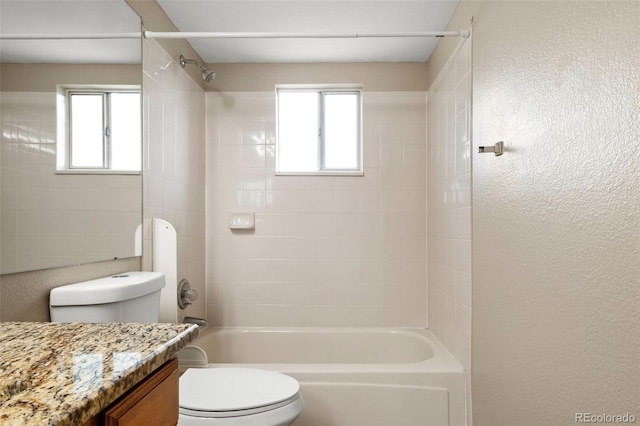 bathroom featuring toilet, plenty of natural light,  shower combination, vanity, and a textured wall