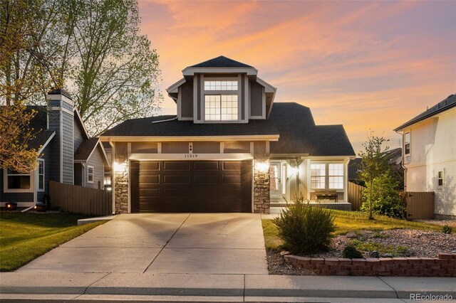 view of front of property featuring fence, concrete driveway, stone siding, and a garage
