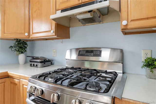 kitchen with under cabinet range hood, light brown cabinets, light countertops, and stainless steel gas stove