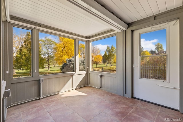 unfurnished sunroom with beamed ceiling, wooden ceiling, and plenty of natural light