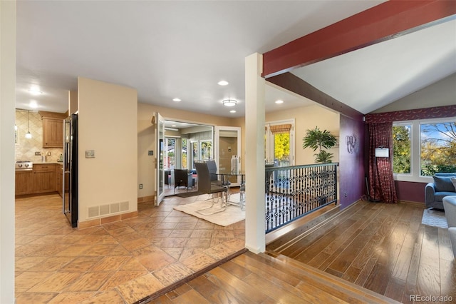 interior space with light hardwood / wood-style flooring and vaulted ceiling with beams