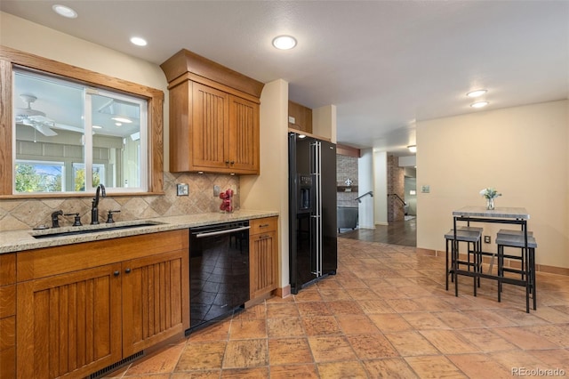 kitchen with sink, black appliances, light stone countertops, tasteful backsplash, and ceiling fan