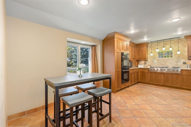 kitchen featuring stainless steel gas cooktop, decorative backsplash, double oven, and hanging light fixtures