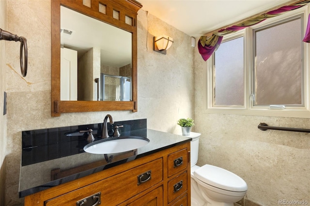 bathroom featuring vanity, toilet, and a shower with door