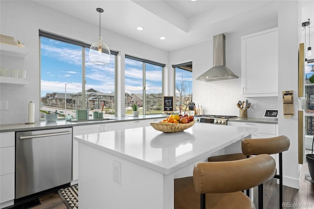 kitchen featuring wall chimney range hood, a sink, a center island, tasteful backsplash, and stainless steel dishwasher