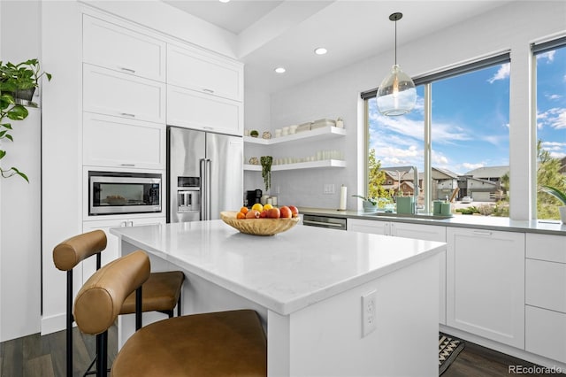 kitchen with dark wood-type flooring, white cabinets, a kitchen island, and stainless steel appliances
