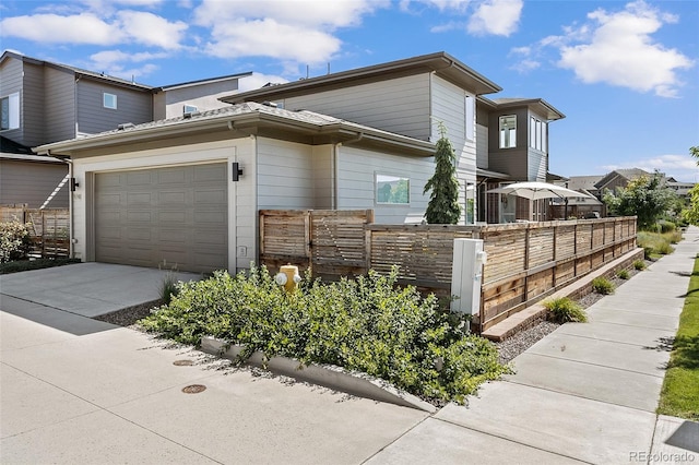 view of property exterior with fence private yard, a garage, and concrete driveway