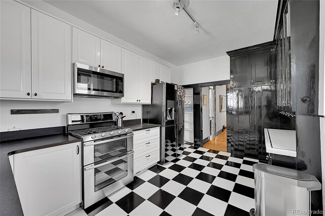 444 S Pearl St, Denver, CO 80209 - kitchen featuring appliances with stainless steel finishes, tile patterned floors, dark countertops, and white cabinets