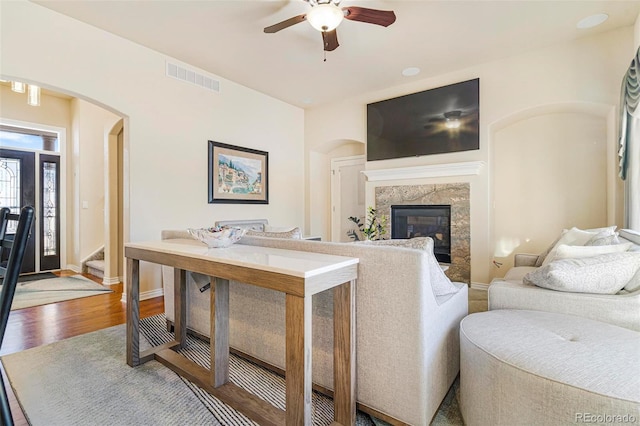 living room featuring arched walkways, visible vents, stairway, a high end fireplace, and wood finished floors