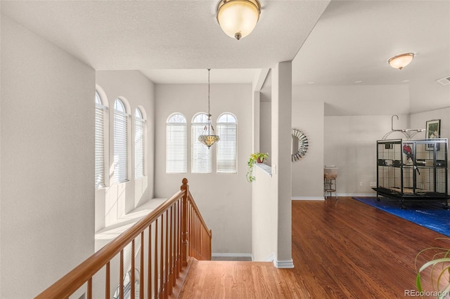 corridor featuring baseboards, visible vents, an upstairs landing, and wood finished floors