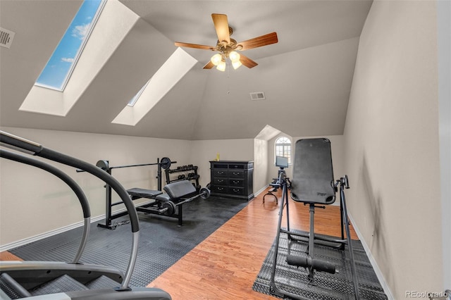 exercise room featuring lofted ceiling, ceiling fan, dark wood-style flooring, visible vents, and baseboards