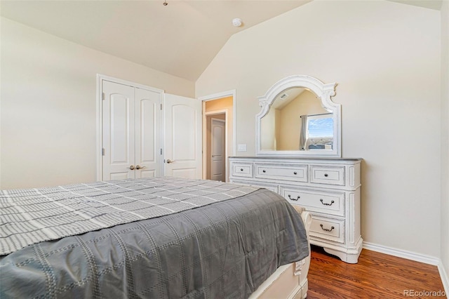 bedroom featuring lofted ceiling, dark wood-style flooring, a closet, and baseboards