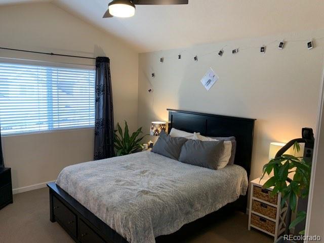 carpeted bedroom with ceiling fan and vaulted ceiling