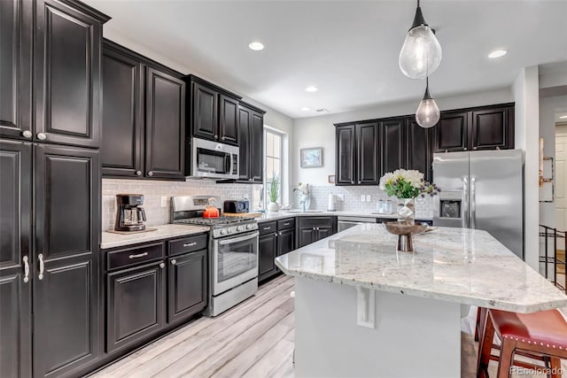 5519 Genoa St, Denver, CO 80249 - kitchen featuring stainless steel appliances, a center island, backsplash, a kitchen breakfast bar, and light wood-type flooring