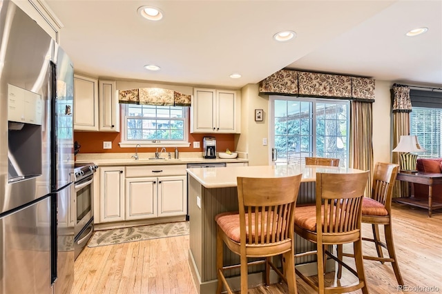 kitchen with a sink, light countertops, light wood-style flooring, stainless steel appliances, and recessed lighting
