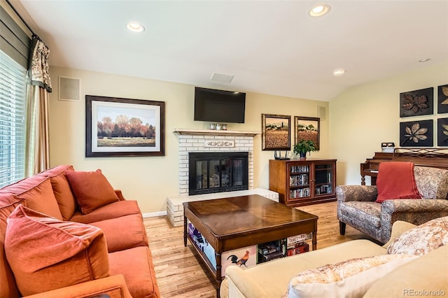 living room featuring baseboards, a fireplace, recessed lighting, and light wood-style flooring