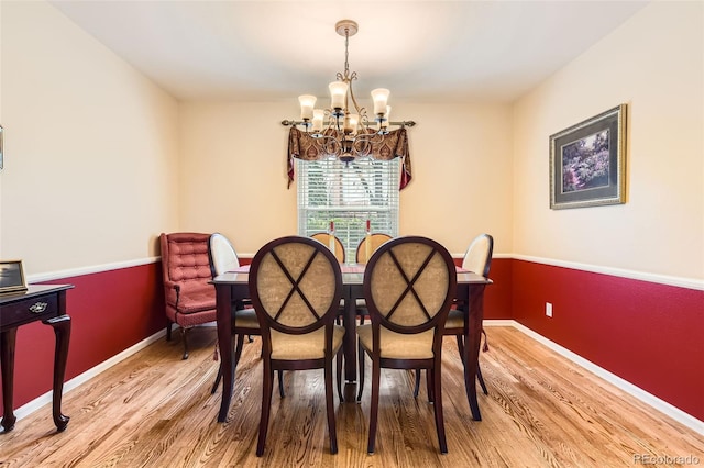 dining room with baseboards, light wood finished floors, and a chandelier