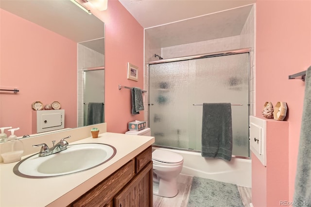 full bathroom with toilet, bath / shower combo with glass door, and vanity