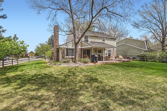 back of property featuring fence private yard, a patio, a chimney, brick siding, and a yard