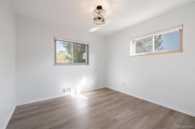 unfurnished room featuring an inviting chandelier and wood-type flooring