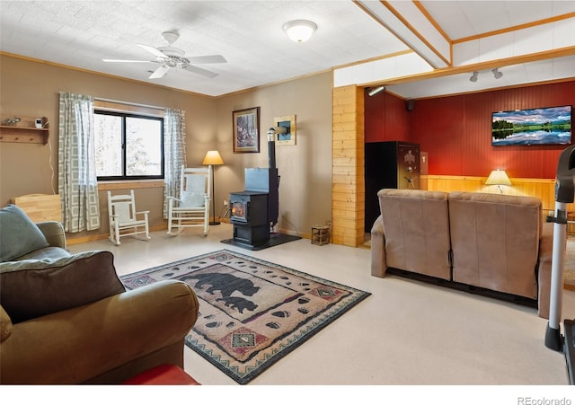 1666 High Creek Rd, Fairplay, CO 80440 - living room featuring wood walls, a wood stove, a ceiling fan, crown molding, and carpet floors