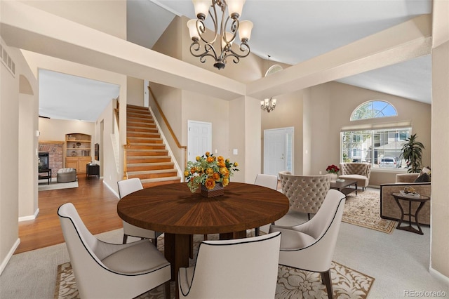 8985 Edgewood Ln, Highlands Ranch, CO 80130 - dining room featuring a chandelier, stairway, wood finished floors, a fireplace, and high vaulted ceiling