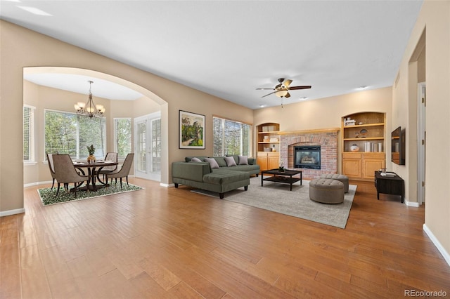 8985 Edgewood Ln, Highlands Ranch, CO 80130 - living room featuring baseboards, ceiling fan, arched walkways, wood finished floors, and a brick fireplace