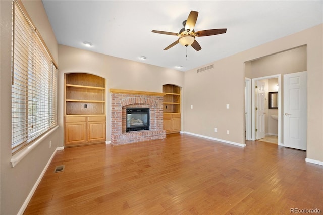 8985 Edgewood Ln, Highlands Ranch, CO 80130 - unfurnished living room featuring baseboards, built in shelves, a ceiling fan, light wood-type flooring, and a fireplace